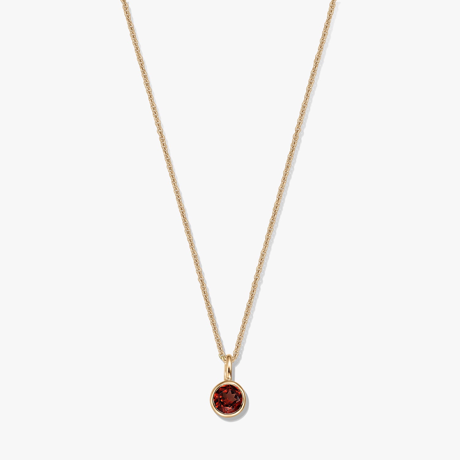 Collier élégant en argent sterling plaqué or avec pendentif en grenat rond serti clos sur une chaîne délicate, isolé sur fond blanc.
