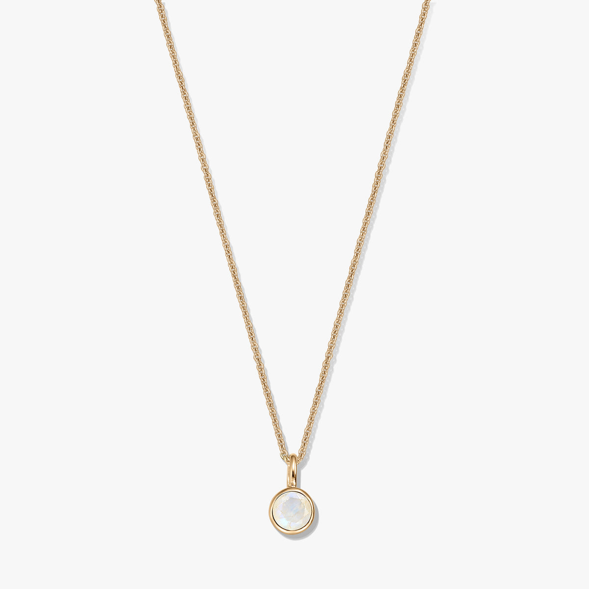 Collier en argent sterling plaqué or avec un petit pendentif pierre de naissance en pierre de lune ronde sertie dans un chaton, centré sur un fond blanc.