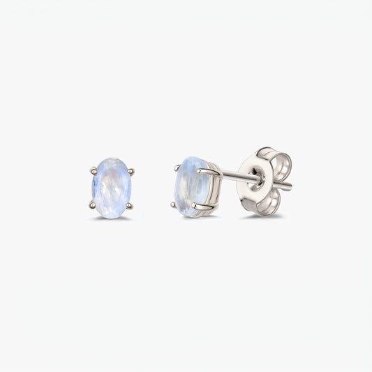 Paire de boucles d’oreilles puces en pierre de lune argentée avec pierres ovales facettées montées sur griffes à quatre branches et fermoirs papillon, présentées sur fond blanc.