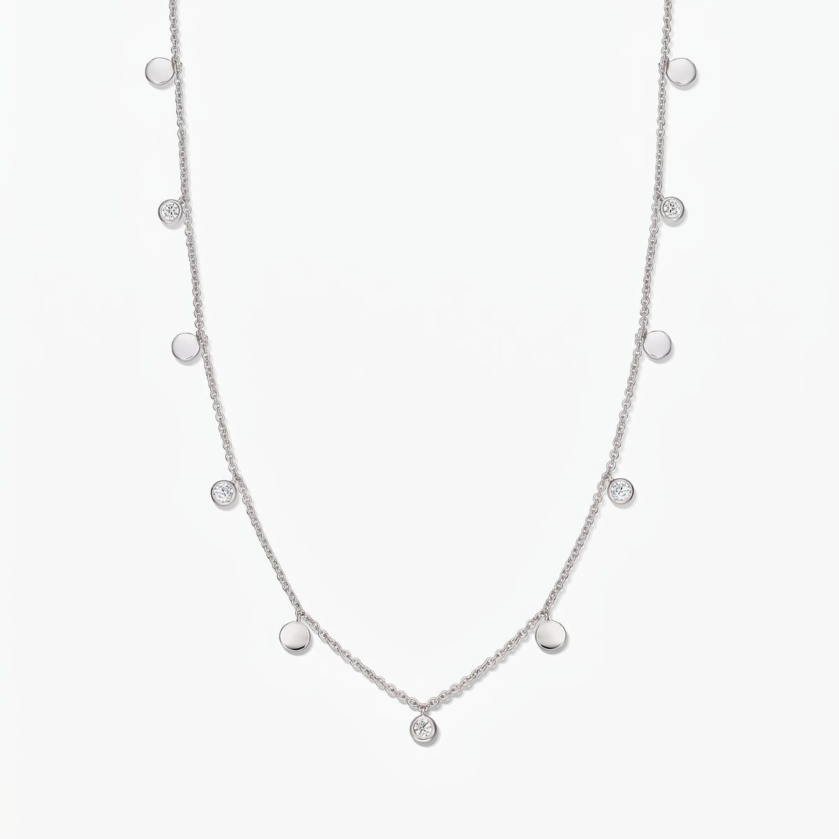 Collier à stations Noora en argent sterling, avec des disques polis alternés et des topazes blanches serties en serti clos, sur fond blanc.