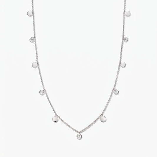 Collier à stations Noora en argent sterling, avec des disques polis alternés et des topazes blanches serties en serti clos, sur fond blanc.
