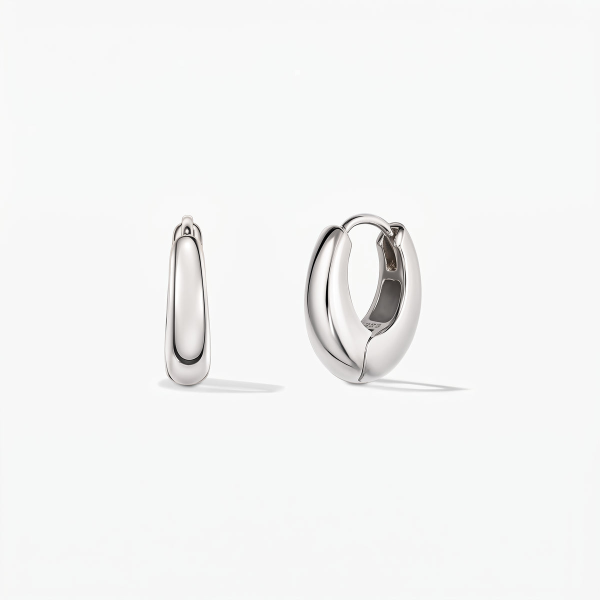 Paire de créoles huggie en argent à mini dôme poli sur fond blanc, vue de face, l’une ouverte révélant la charnière du fermoir.