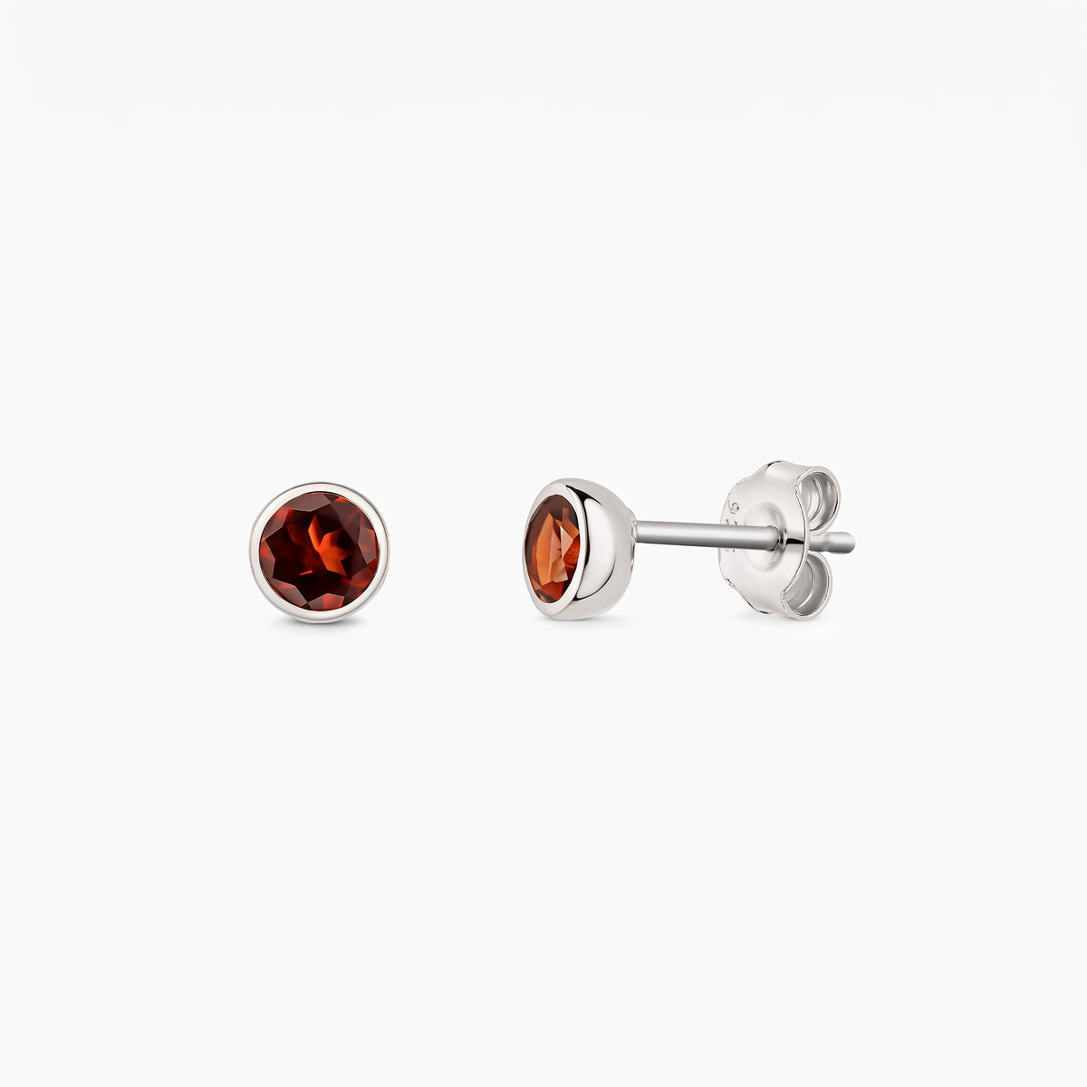 Paire de boucles d'oreilles puces en argent sterling avec pierres de grenat rondes, vues de face et de profil sur fond blanc, fermoirs papillon visibles.