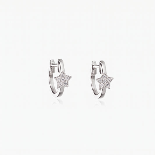 Paire de créoles huggie en argent sterling 925 plaqué rhodium avec de petits pendentifs étoile sertis de zirconias transparents, sur fond blanc.