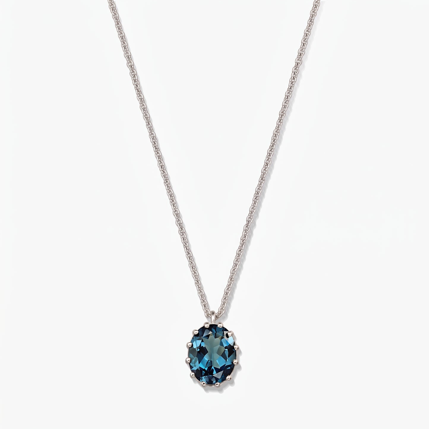 Collier en argent sterling avec un pendentif ovale en topaze bleu de Londres sur fond blanc.