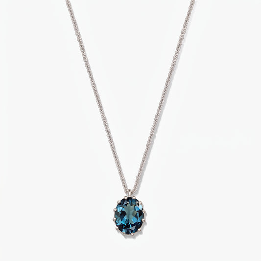 Collier en argent sterling avec un pendentif ovale en topaze bleu de Londres sur fond blanc.