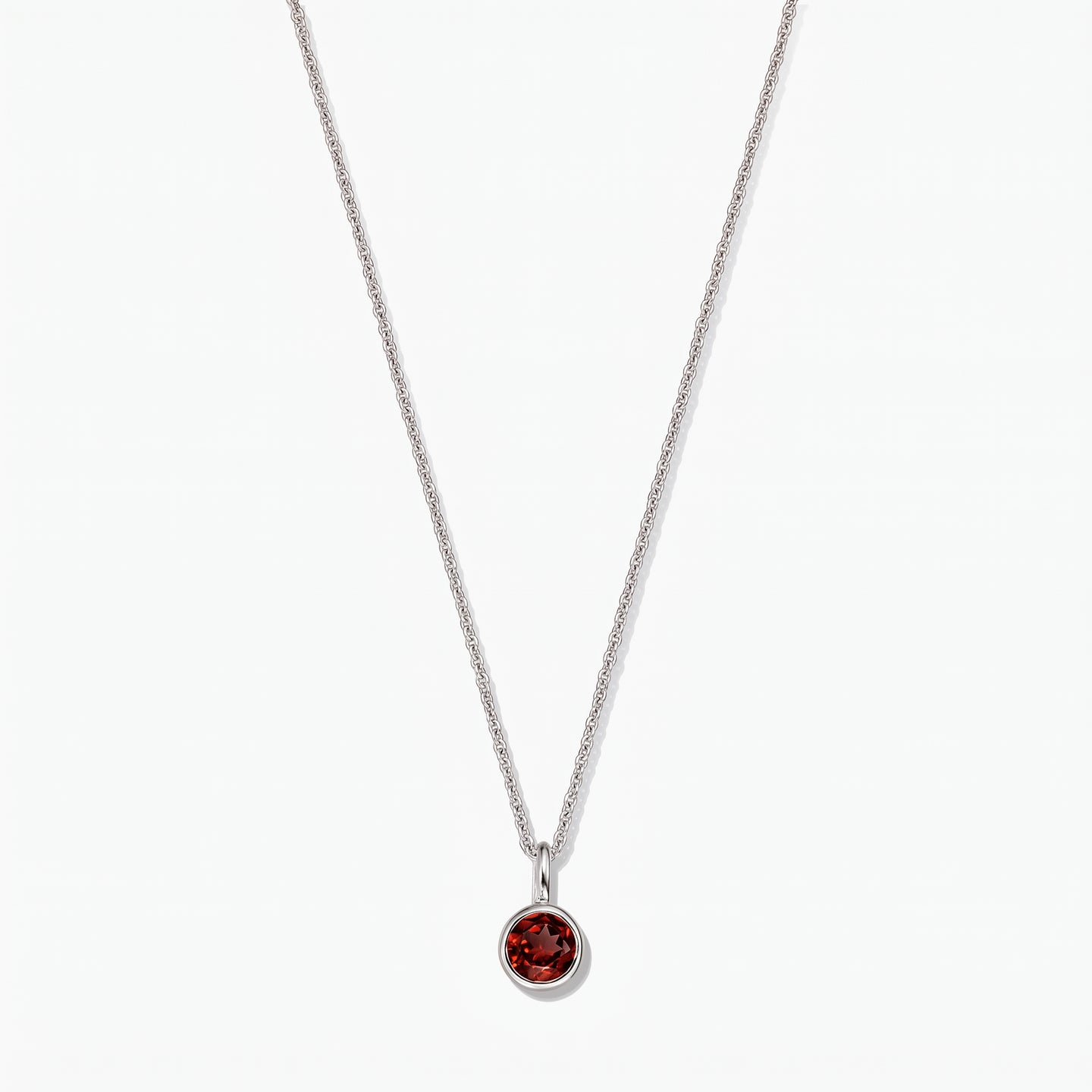 Collier pierre de naissance en argent sterling avec pendentif en grenat rond serti clos sur fond blanc.