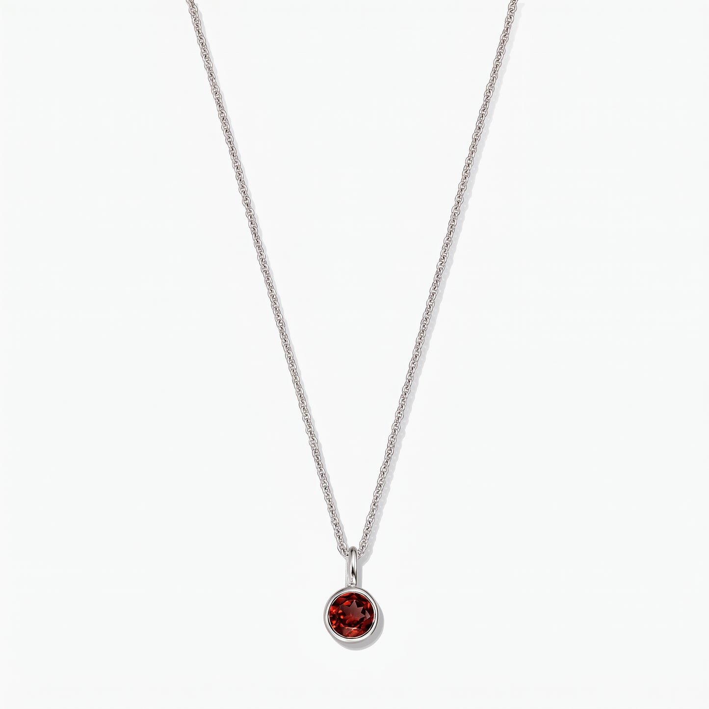 Collier pierre de naissance en argent sterling avec pendentif en grenat rond serti clos sur fond blanc.