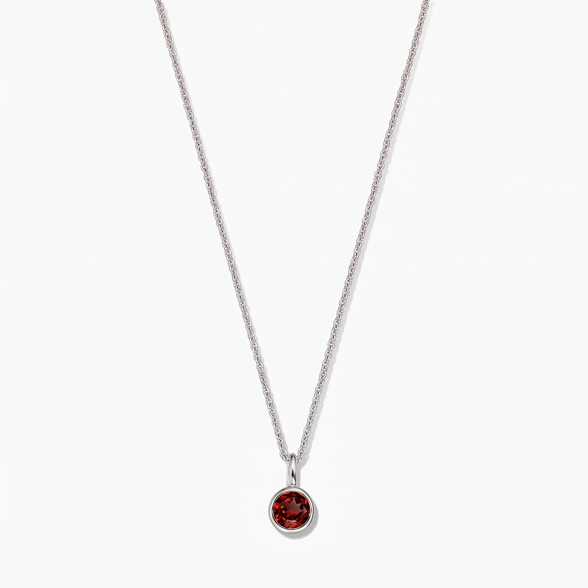 Collier pierre de naissance en argent sterling avec pendentif en grenat rond serti clos sur fond blanc.