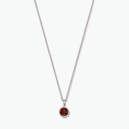 Collier pierre de naissance en argent sterling avec pendentif en grenat rond serti clos sur fond blanc.