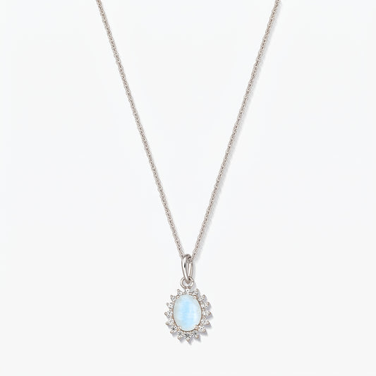 Collier en argent sterling orné d’un pendentif ovale en pierre de lune bleu clair, bordé de petites pierres transparentes, sur une chaîne fine, photographié sur fond blanc.