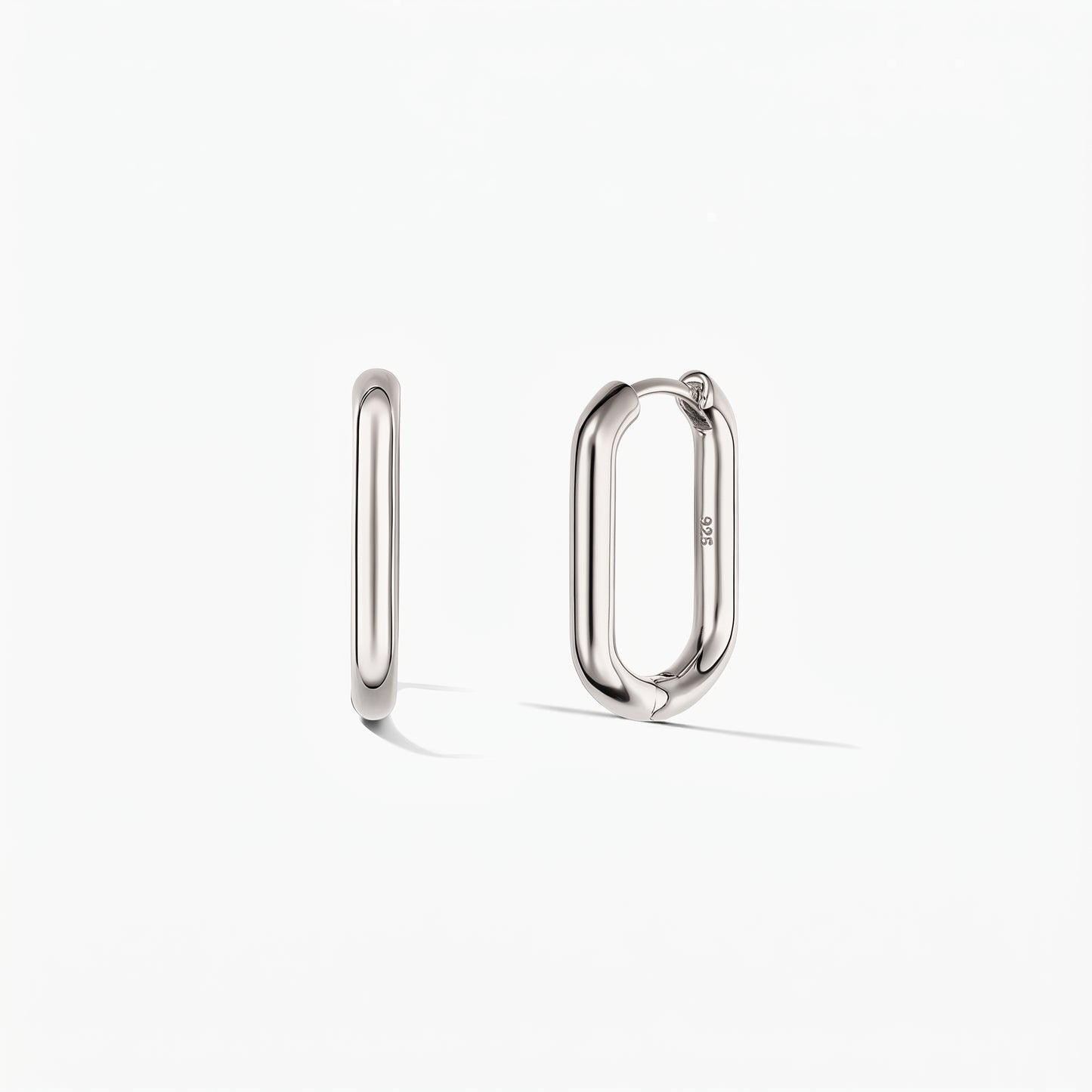 Paire de créoles carrées en argent sur fond blanc, l'une vue de côté et l'autre légèrement ouverte pour révéler le fermoir à charnière.