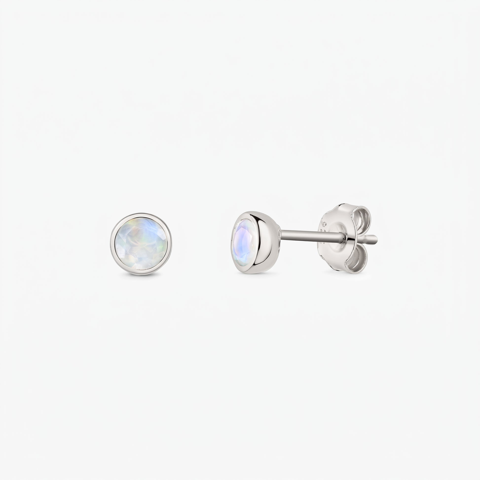 Paire de puces d’oreilles en pierre de lune en argent sterling 925 sur fond blanc, vues de face et de côté, avec fermoirs poussette et pierres rondes iridescentes serties en clos.