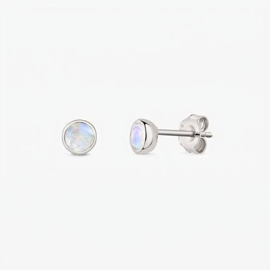 Paire de puces d’oreilles en pierre de lune en argent sterling 925 sur fond blanc, vues de face et de côté, avec fermoirs poussette et pierres rondes iridescentes serties en clos.