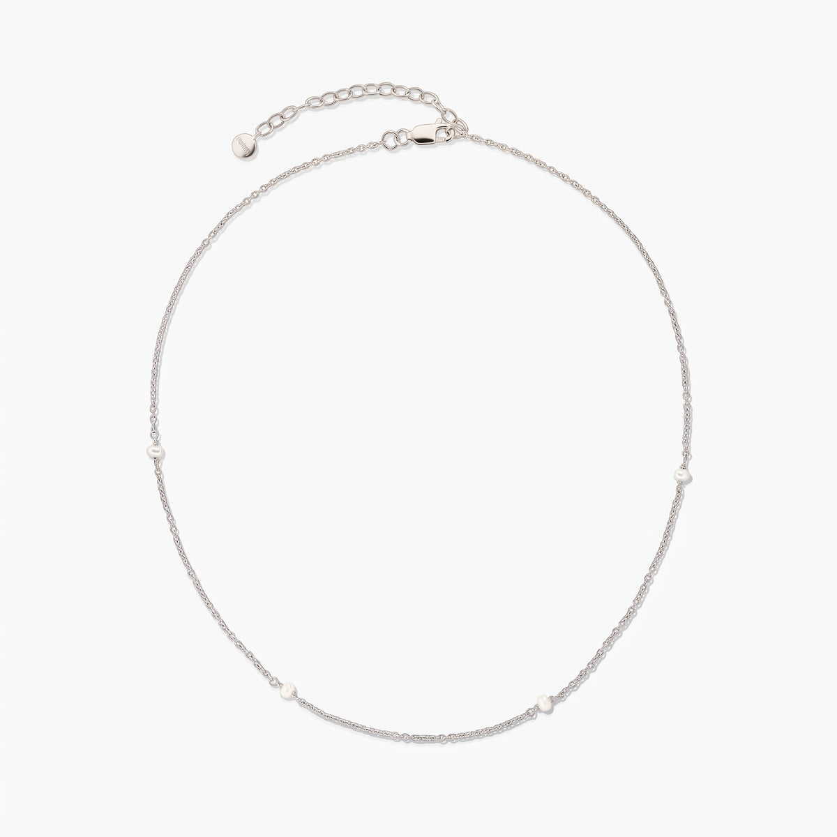 Collier chaîne en argent délicat avec de petites perles blanches espacées, présenté en cercle sur fond blanc avec une rallonge ajustable et un fermoir mousqueton.